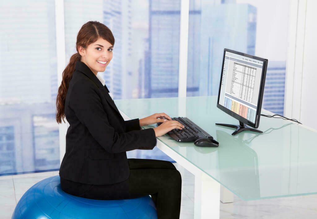 Kvinde på kontorarbejde sidder på en pilates bold